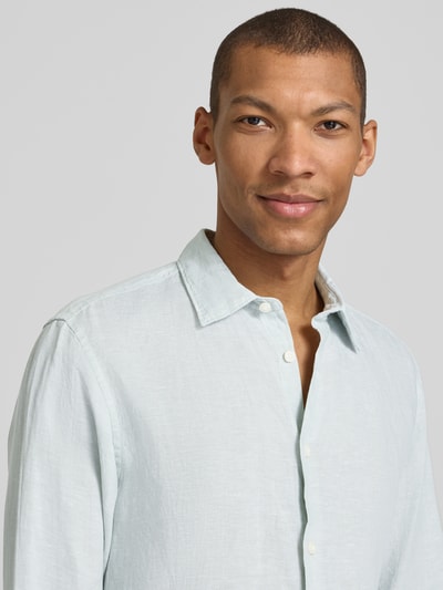 Männermodel trägt Regular Fit Freizeithemd aus reinem Leinen Modell 'REGKYLIAN' von SELECTED HOMME in Hellblau, Nahaufnahme Oberkörper.