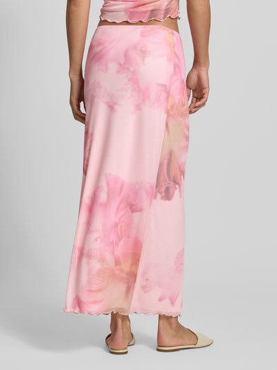 Frauenmodel trägt Straight Fit Maxirock mit floralem Allover-Print von REVIEW in Rosa mit floraler Musterung, Elastischer-Material-Mix, Mesh, blickdichter Unterrock, Ganzkörperansicht Rückansicht.