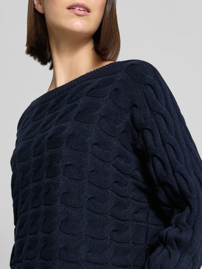 Frauenmodel trägt Relaxed Fit Strickpullover aus Baumwoll-Mix mit Zopfmuster von Oui, navy, U-Boot-Ausschnitt, Nahaufnahme Oberkörper.
