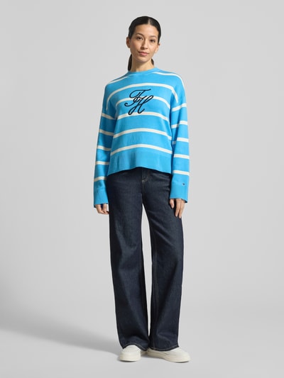 Frauenmodel trägt Regular Fit Sweatshirt aus reiner Baumwolle von Tommy Hilfiger in Blau mit weißen Streifen, Logo-Stitching, Feinstrick, Ganzkörperansicht von vorne.