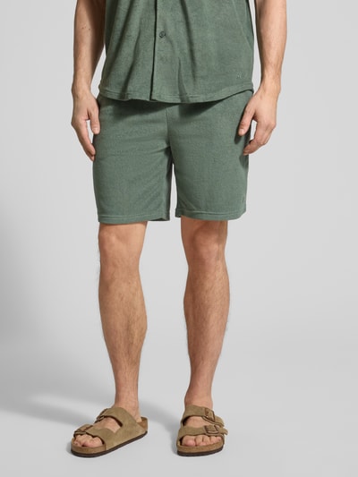 Männermodel trägt Shorts mit elastischem Bund von MCNEAL aus grünem Baumwoll-Mix, Regular Fit, Nahaufnahme Oberkörper bis Knie.