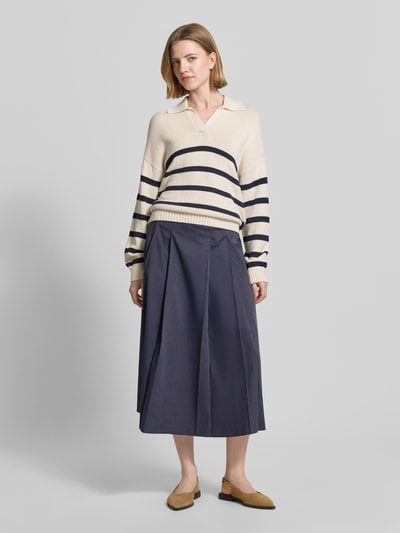 Frauenmodel trägt Midirock mit Nahtreißverschluss Modell 'Vivian' von Raffaello Rossi, Gelegte Falten, Logo-Stitching, Ganzkörperansicht von vorne.