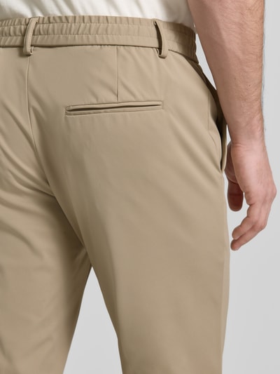 Männermodel trägt Sweatpants mit elastischem Bund von Guess in Beige, glatte Textur, Gesäßtasche, Nahaufnahme Rückansicht, Material-Mix mit Stretch