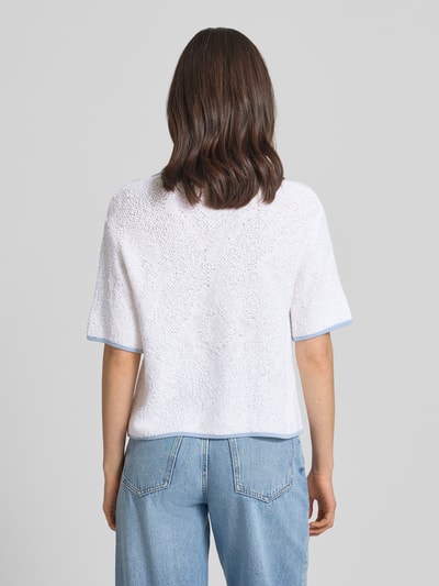 Frauenmodel trägt Strickjacke mit Viskose-Anteil von Marc Cain, weiß mit hellblauen Abschlüssen, gerader Schnitt, Rückansicht Ganzkörperansicht.