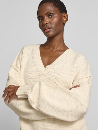 Frauenmodel trägt Oversized Pullover in Strick-Optik von black palms aus Baumwoll-Mix, V-Ausschnitt, kremfarben, Nahaufnahme Oberkörper.