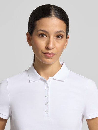 Frauenmodel trägt Slim Fit Poloshirt mit Knopfleiste von Christian Berg Woman aus Baumwoll-Elasthan-Mix in Weiß, Nahaufnahme Oberkörper.