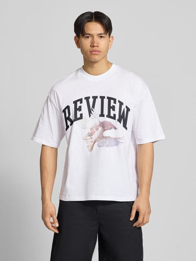 Männermodel trägt T-Shirt mit Logo- und Motiv-Print von REVIEW, weiße Reine Baumwolle, Loose-Fit, Gerippter Rundhalsausschnitt, Ganzkörperansicht von vorne. Rückenlänge bei Größe M: 70 cm.
