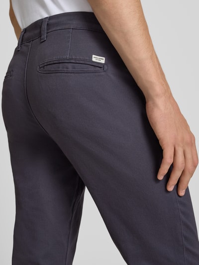 Męskamodel nosi Slim Fit Hose mit Gesäßtaschen Modell 'MARCO' von Jack & Jones, mieszanka bawełny i elastanu, krój slim fit, ciemnoszary kolor, gładka tekstura, kieszenie z tyłu, Szerokość w rozmiarze 32/32: 42 cm, Długość wewnętrzna nogawki w rozmiarze 32/32: 78 cm, zbliżenie tyłu