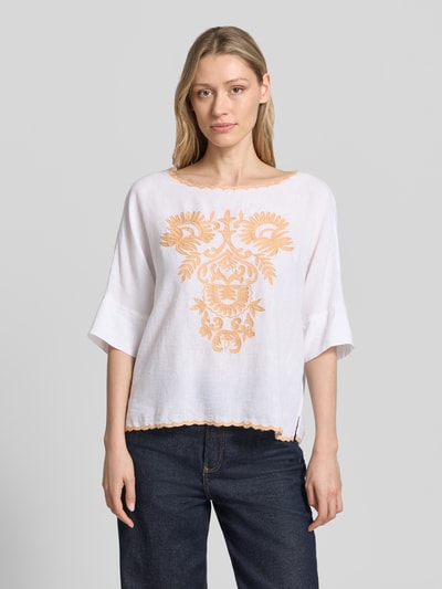 Frauenmodel trägt Blusenshirt mit Leinen-Anteil und Motiv-Stitching von Christian Berg Woman, weiß mit orange, Viskose-Mix, Loose-Fit, U-Boot-Ausschnitt, Motiv-Stitching, Ganzkörperansicht von vorne.