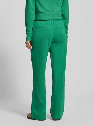 Kobiece modelka nosi zielone Sweatpants mit elastischem Bund von Christian Berg Woman, luźny krój, kieszenie, widok od tyłu.