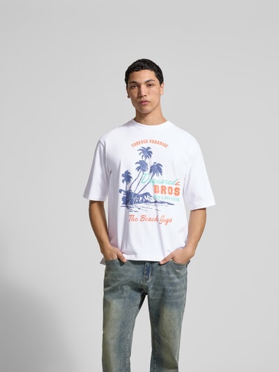 Männermodel trägt Loose Fit T-Shirt aus reiner Baumwolle von Dsquared2 mit Motiv-Print und Rundhalsausschnitt, Vorderansicht, Ganzkörperansicht von vorne.