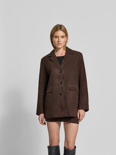 Frauenmodel trägt Blazer aus echtem Ziegenvelours von ROTATE in Dunkelbraun, Oversized Fit, Reverskragen, Knopfleiste, Pattentaschen, Ganzkörperansicht von vorne.