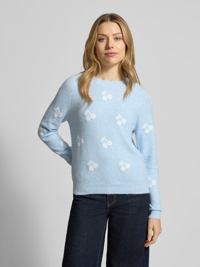 Frauenmodel trägt Regular Fit Strickpullover mit Intarsien Modell 'DOFFY INTARSIA' von Vero Moda in Hellblau mit Allover-Muster, Ganzkörperansicht von vorne.