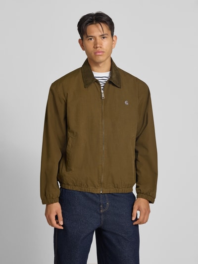 Männermodel trägt Jacke mit Label-Stitching Modell 'Madison' von Carhartt Work In Progress aus Baumwolle, Regular Fit, Ganzkörperansicht von vorne.