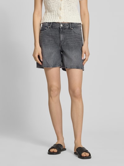 Frauenmodel trägt Shorts in Denim-Optik Modell 'Seville' von JJXX, schwarze Farbe, 5-Pocket-Design, Ganzkörperansicht von vorne.