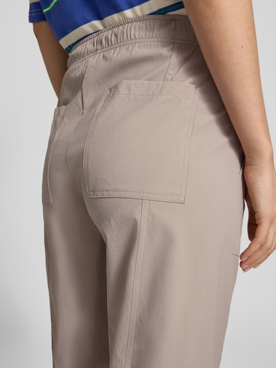 Kobieta prezentuje spodnie materiałowe Regular Fit Stoffhose mit Eingrifftaschen Modell 'OPHELIA' od Cambio, beżowy kolor, wpuszczane kieszenie, elastyczny pas, skrócona nogawka, szerokość w rozmiarze 36: 42 cm, długość wewnętrzna nogawki: 69 cm, detal z tyłu, zbliżenie na biodra.