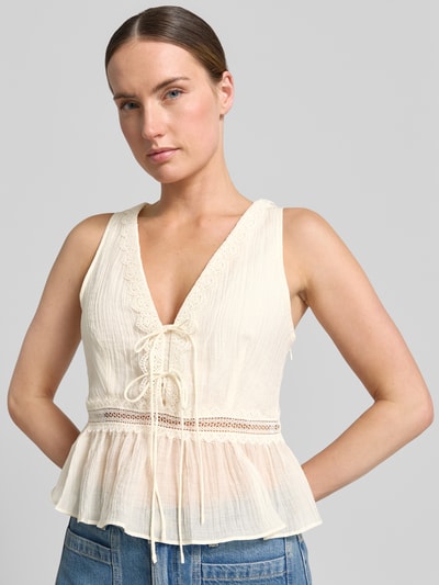 Frauenmodel trägt Top aus Lyocell-Mix mit Zierschleifen Modell 'Elena' von Mango in Creme mit taillierter Passform, Nahaufnahme Oberkörper.