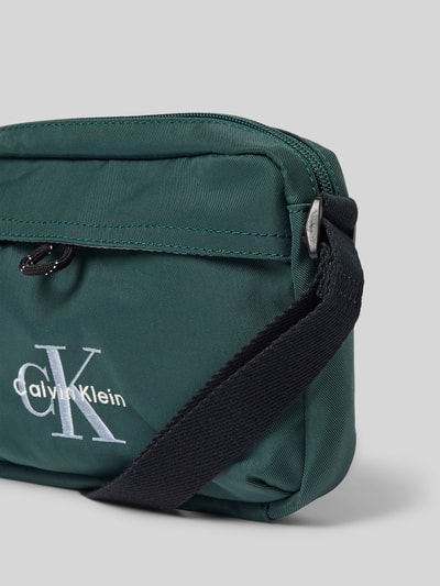 Produktfoto, Crossbody Bag mit Label-Stitching von CK Calvin Klein in Dunkelgrün mit Hauptfach, Reißverschluss, verstellbarem Schulterriemen, 21x15x6 cm.