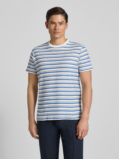 Männermodel trägt T-Shirt mit Streifenmuster Modell 'MARINA' von Guess in Blau und Weiß, reine Baumwolle, Regular Fit, Ganzkörperansicht von vorne.