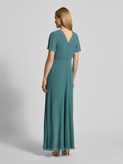 Frauenmodel trägt Damen Abendkleid mit Spitzenbesatz von Christian Berg Cocktail in Türkis, taillierte Passform, semitransparent, Ganzkörperansicht Rückansicht.