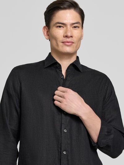 Męski model nosi Regular Fit Business-Hemd aus Leinen mit Kentkragen od SEIDENSTICKER, czarna struktura, krój regular fit, czysta len, zapięcie na guziki, długość tyłu w rozmiarze 40: 79 cm, szerokość w rozmiarze 40: 46 cm, długość rękawa w rozmiarze 40: 67 cm, półzbliżenie na górną część ciała z przodu