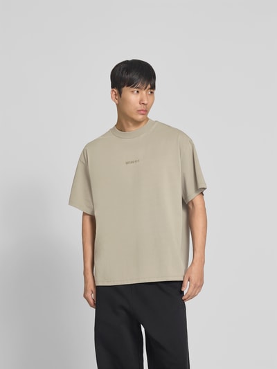 Männermodel trägt Relaxed Fit T-Shirt mit Logo-Stitching von WON HUNDRED aus reiner Baumwolle, beige, Rundhalsausschnitt, Ganzkörperansicht von vorne.