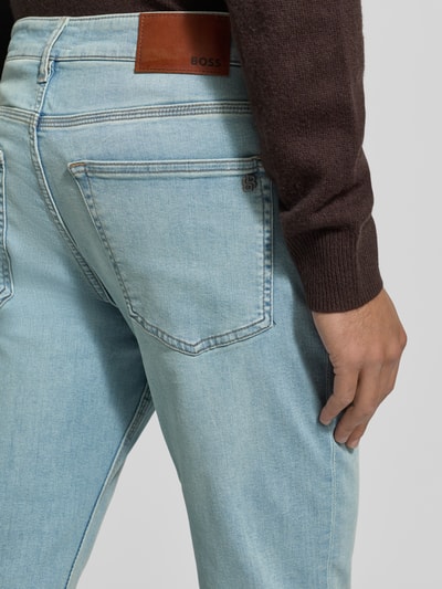 Męski model nosi Tapered Fit Jeans aus Baumwoll-Mix Model 'ONYX' od BOSS Orange, jasny denim, mieszanka bawełny, naszywka z logo, 5 kieszeni, krój tapered fit, zdjęcie szczegółowe tylu.