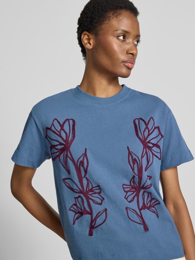 Vrouwenmodel draagt Regular Fit T-shirt uit zuivere katoen van Jake*s Casual in blauw met rode bloemenprint, nahaufnahme bovenlichaam.
