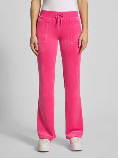 Kobiece model prezentuje spodnie dresowe Low Rise Sweatpants z elastycznym pasem Model 'LAYLA' od Juicy Couture, mieszanka bawełny z dodatkiem streczu, rozkloszowany krój, wpuszczane kieszenie, kolor intensywnie różowy, długość wewnętrzna nogawki 39 cm, widok na całe ciało z przodu.