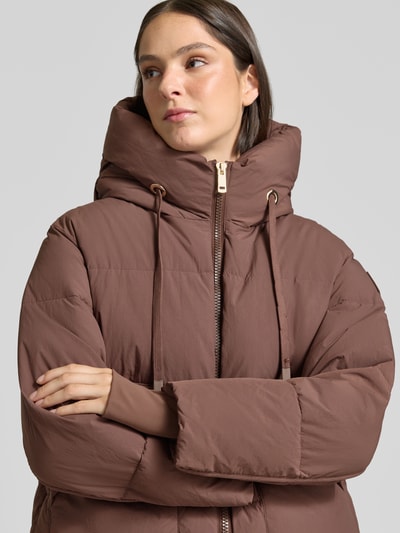 Kobiece model prezentuje Regular Fit Jacke in Stepp-Optik Modell 'Ollie' von MOS MOSH, brązowy kolor, z efektem pikowania, kaptur z tunelem, długość tyłu w rozmiarze S: 65 cm, szerokość ramion w rozmiarze S: 52 cm, szerokość klatki piersiowej w rozmiarze S: 63 cm, długość rękawów w rozmiarze S: 68 cm, zbliżenie na górną część ciała.