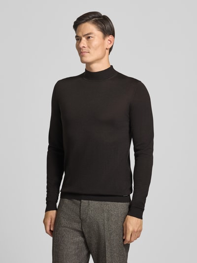 Männermodel trägt Strickpullover aus Schurwolle mit Stehkragen von ROY ROBSON in Schwarz, feine Struktur, Slim Fit, Ganzkörperansicht von vorne.