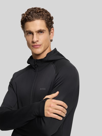 Männermodel trägt Regular Fit Trainingsjacke aus schnell trocknendem Gewebe Modell 'SICON ACTIVE' von BOSS Green in Schwarz, Nahaufnahme Oberkörper