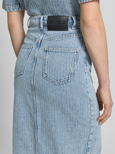 Frauenmodel trägt Figurbetonter Jeansrock aus reiner Baumwolle Modell 'GATJE' von HUGO in Denim-Optik mit Strukturmuster, Label-Patch, 5-Pocket-Design, Gürtelschlaufen, Frontschlitz, Maxi-Länge, Nahaufnahme Rückansicht.