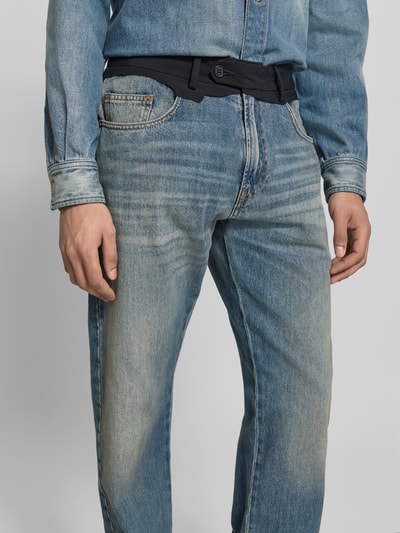 Männermodel trägt Straight Fit Jeans mit kontrastivem Bund von MM6 Maison Margiela, Reine Baumwolle, 5-Pocket-Design, Knopf- und Reißverschluss, Nahaufnahme Oberkörper.