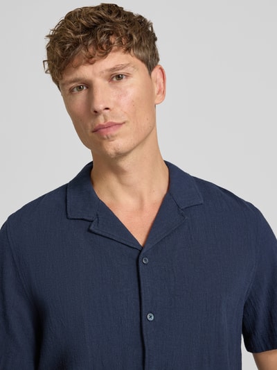 Männermodel trägt Resort Fit Freizeithemd aus reiner Baumwolle von s.Oliver RED LABEL in Dunkelblau, Nahaufnahme Oberkörper.