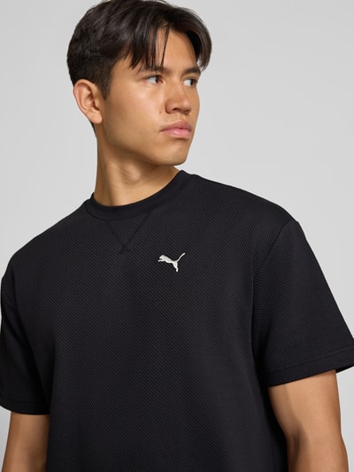 Männermodel trägt schwarzes Relaxed Fit T-Shirt aus reiner Baumwolle Modell 'ESS ELEVATED' von PUMA, Herren T-Shirt von PUMA Performance, Nahaufnahme Oberkörper.