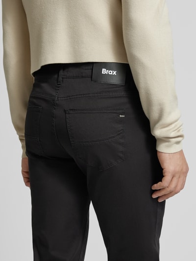 Männermodel trägt Slim Fit Stoffhose mit Lyocell-Anteil Modell 'Cadiz' von Brax, 5-pocket-design, zwarte kleur, detailopname rug, elastische katoenmix context: heren stofhose, knoop- en ritssluiting, taillewijdte 107 cm, binnenbeenlengte 81 cm
