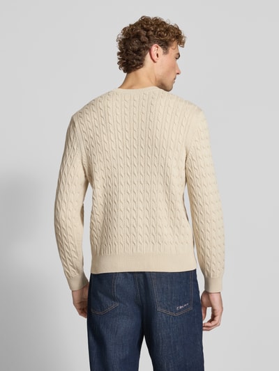 Männermodel trägt Regular Fit Strickpullover aus Baumwoll-Mix von Lacoste in Beige mit Zopfmuster, Herren Strickjacke, Ganzkörperansicht Rückansicht.