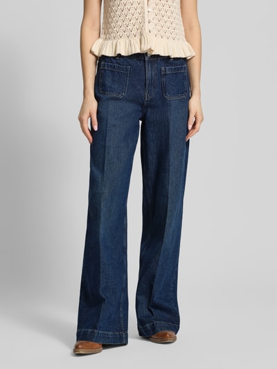 Kobiece modelka nosi Wide Leg Jeans mit aufgesetzten Taschen od Review, ciemnoniebieski jeans, czysta bawełna, szeroki krój, kieszenie naszyte, zaprasowane fałdy, szerokość w rozmiarze 27: 38 cm, długość nogawki wewnętrznej w rozmiarze 27: 82 cm, zdjęcie całej sylwetki z przodu.