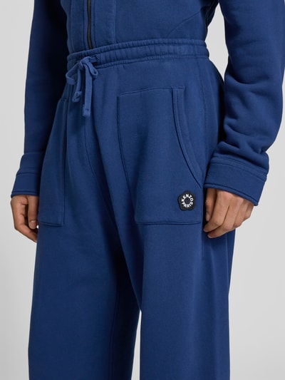 Männermodel trägt Straight Fit Sweatpants mit Logo-Detail von Kenzo aus reiner Baumwolle in Blau mit aufgesetzten Taschen, Nahaufnahme Oberkörper.