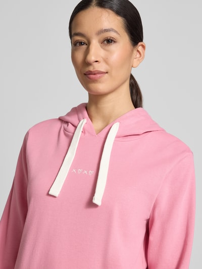Vrouwenmodel draagt Regular Fit Hoodie aus Baumwoll-Mix van Tom Tailor Denim in effen roze sweatstof met borduursel, kap met tunnelkoord, lange mouw, geribde boorden en zijsplitten, Nahaufnahme bovenlichaam.