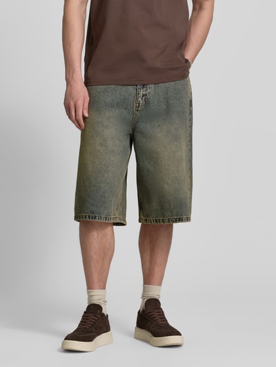 Männermodel trägt Jeansshorts mit Eingrifftaschen Modell 'Yuto Aged' von WOODBIRD aus reiner Baumwolle im Relaxed-Fit, Ganzkörperansicht von vorne.