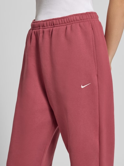 Frauenmodel trägt Oversized Sweathose aus Baumwoll-Mix von Nike in Altrosa mit glatter Oberfläche, Nahaufnahme Oberkörper. Damen Sweathose von Nike