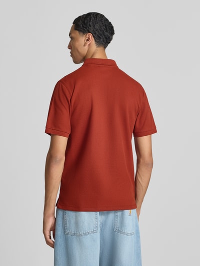 Männermodel trägt Slim Fit Poloshirt mit Label-Stitching Modell 'AUSTIN' von JACK & JONES in Rot, stretchiger Baumwollmix, Ganzkörperansicht Rückansicht.