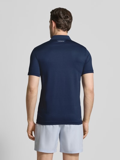 Männermodel trägt Slim Fit Poloshirt aus schnelltrocknendem Material von Lacoste Sport, Optik: Unifarben, Ganzkörperansicht Rückansicht.