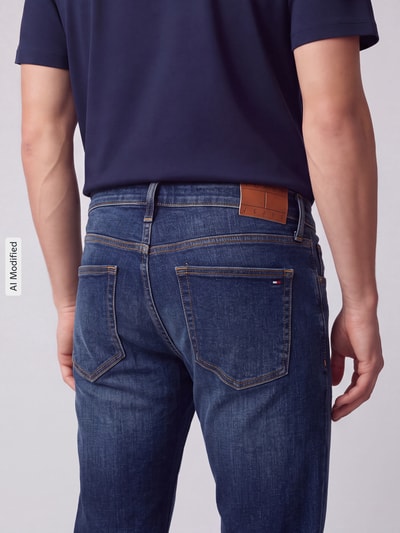 Männermodel trägt Slim Fit Jeans aus Baumwoll-Mix Modell 'Scanton' von Tommy Jeans in dunkelblauem Denim mit Label Patch, Ganzkörperansicht Rückansicht, KI-modifiziertes Bild