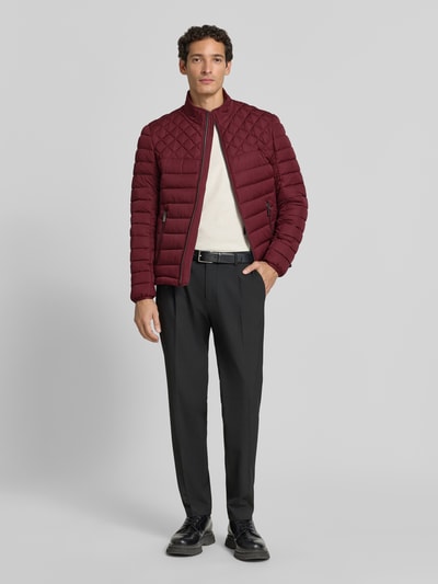 Männermodel trägt Steppjacke mit Stehkragen und Reißverschlusstaschen von Christian Berg Men in Dunkelrot, Regular Fit, Ganzkörperansicht von vorne.