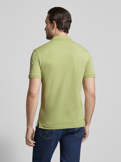 Männermodel trägt Slim Fit Poloshirt aus reiner Baumwolle von Lacoste in hellem Grün, unifarben, Piqué-Struktur, Ganzkörperansicht Rückansicht.