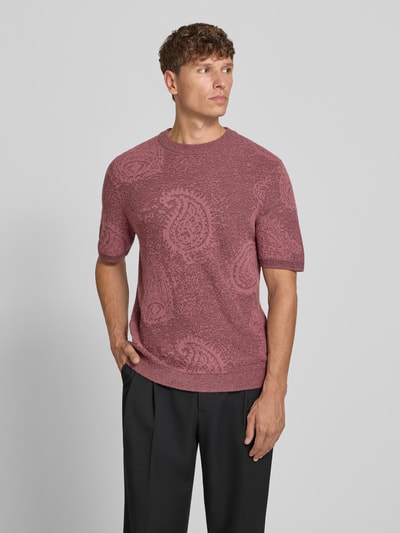 Męski model nosi Strickshirt im Allover-Look mit Rundhalsausschnitt von Jake*s Studio Men, mieszanka bawełny, krój slim fit, wzór na całej powierzchni, okrągły dekolt, długość tyłu w rozmiarze M: 71 cm, długość rękawów w rozmiarze M: 39 cm, odcień różu, teksturowany materiał, gładkie ciemne spodnie, całkowity widok z przodu.