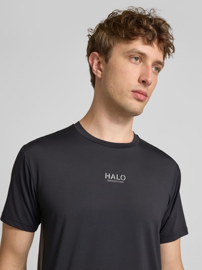 Männermodel trägt Herren T-Shirt mit Logo Modell 'DIVISION' von HALO, Material-Mix mit Stretch-Anteil, Regular-Fit, Rundhalsausschnitt, Logo-Details, Farbe Dunkelgrau, glatte Textur, Rückenlänge bei Größe M 69 cm, Nahaufnahme Oberkörper.